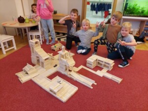 Dzieci pozują z wykonaną przez siebie budowlą z drewnianych klocków