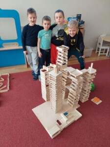 Dzieci pozują z wykonaną przez siebie budowlą z drewnianych klocków