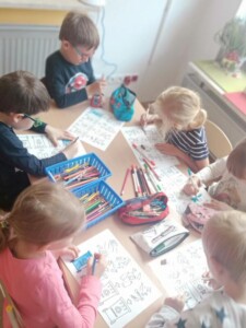 Grupa dzieci koloruje przy stoliku