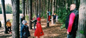 Dzieci stoją między drzewami w lesie.