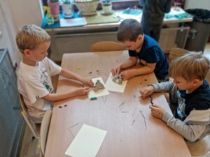 Chłopcy siedzą przy stole, tworzą konstrukcje z plasteliny