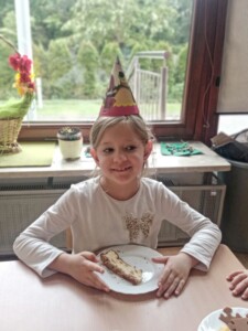 Dziewczynka w czapce urodzinowej siedzi przy stole