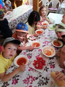 Dzieci siedzą przy stole i jedzą zupę