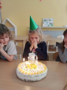 Dziewczynka w czapeczce urodzinowej będzie zdmuchiwać świeczki na torcie