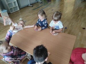 Dzieci przy stołach badają zmysłem dotyku woreczki strunowe z żelem w środku.