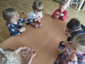 Dzieci przy stołach badają zmysłem dotyku woreczki strunowe z żelem w środku.