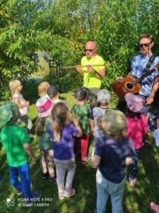 Mężczyźni pokazują grupie dzieci gitarę i flet. 