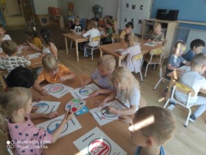 Dzieci przy stolikach malują farbami kropki.