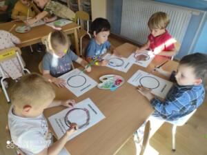 Pięcioro dzieci przy stole maluje farbami kropki.