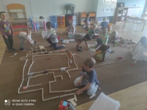 Grupa dzieci bawi się na dywanie klockami.