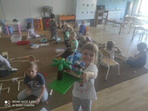 Grupa dzieci bawi się na dywanie klockami.