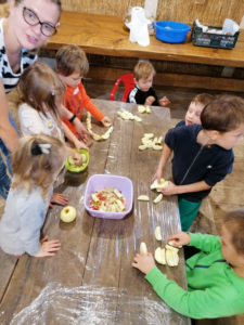 grupa dzieci obiera i kroi jabłka