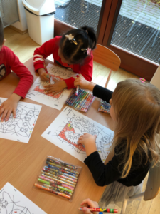 troje dzieci przy stoliku koloruje godło Polski