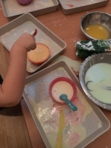 ręka dziecka przekłada masę z miski do miski