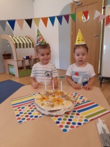 Dzieci w urodzinowych czapeczkach przy torcie
